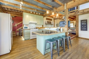 A kitchen with a central island, bar stools, and a microwave.