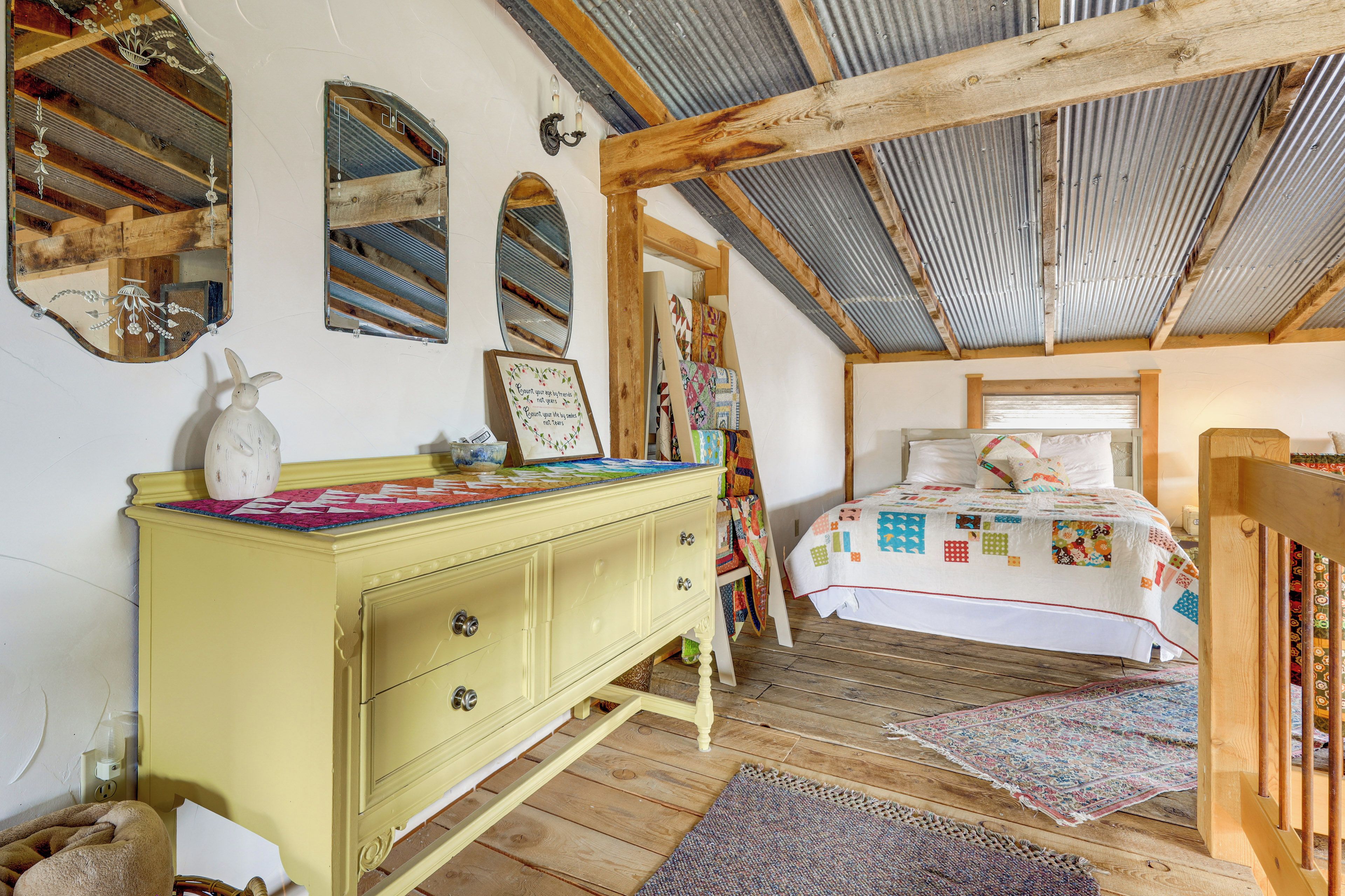 Un dormitorio acogedor con una cama de madera, un aparador amarillo y un espejo en la pared.
