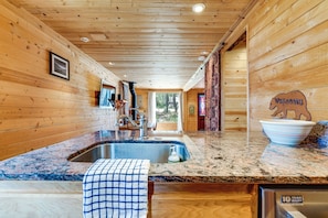 Ein Holzinterieur mit einer Küchenzeile, einer Arbeitsplatte aus Granit, einer Spüle aus Edelstahl und einem Schild für eine 10-jährige Garantie.