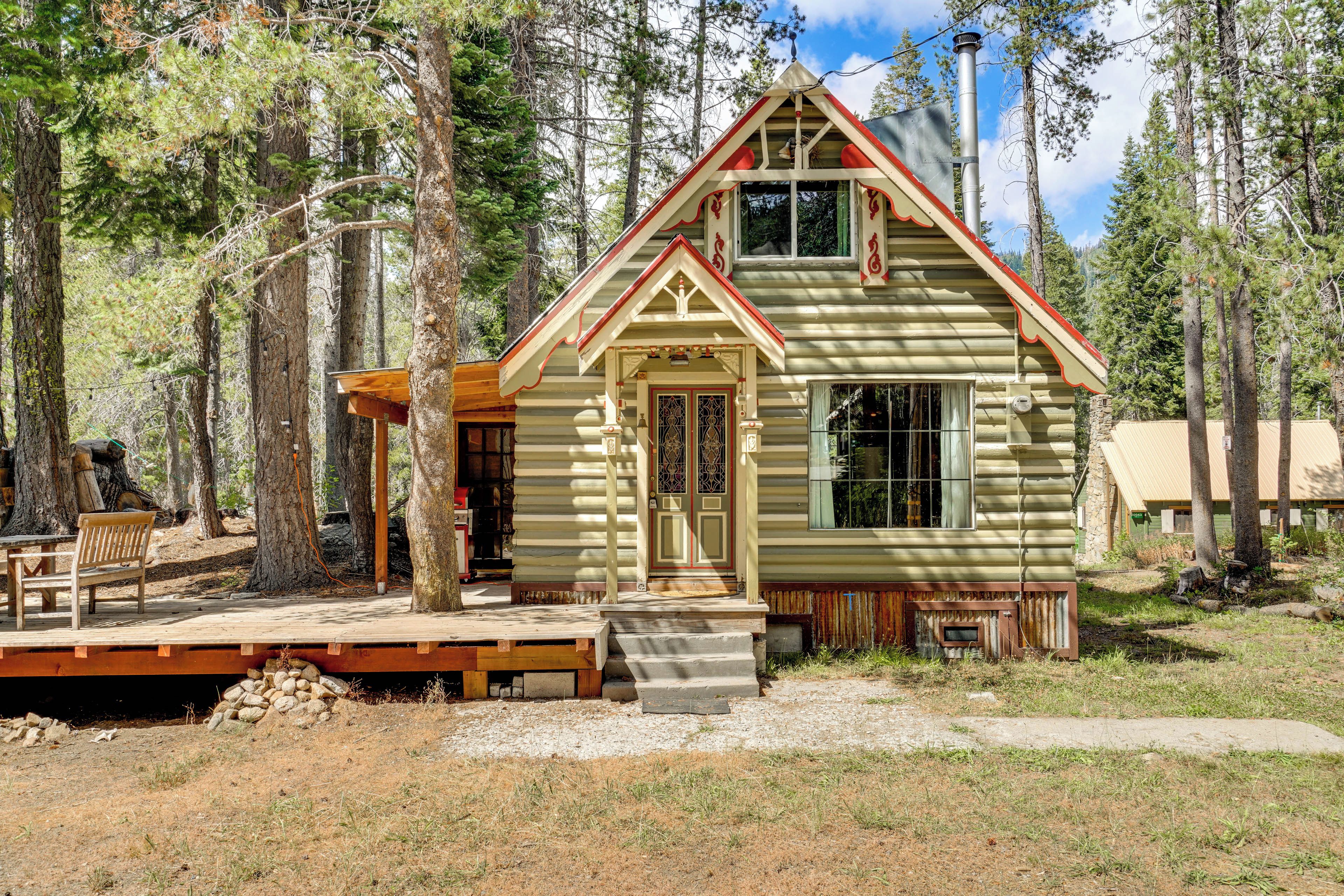 Une cabane en rondins avec un porche à l’avant, une cheminée et une terrasse.