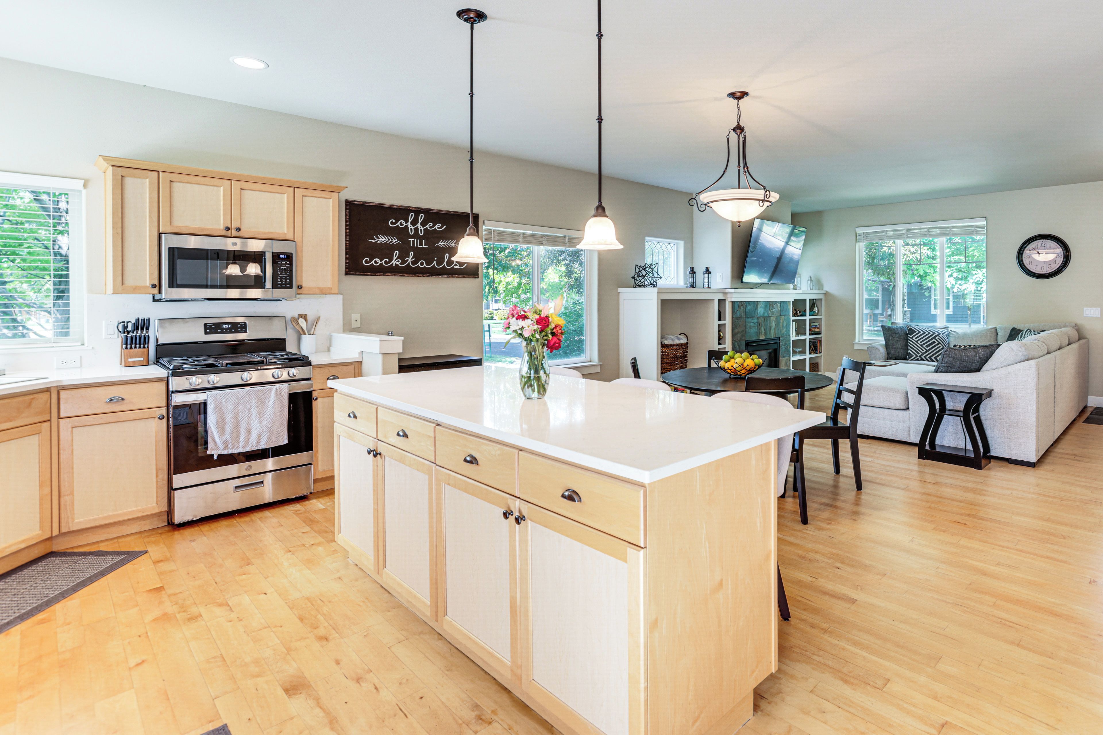 A modern kitchen with wooden cabinets, a central island, and a dining area with a sofa and chairs.