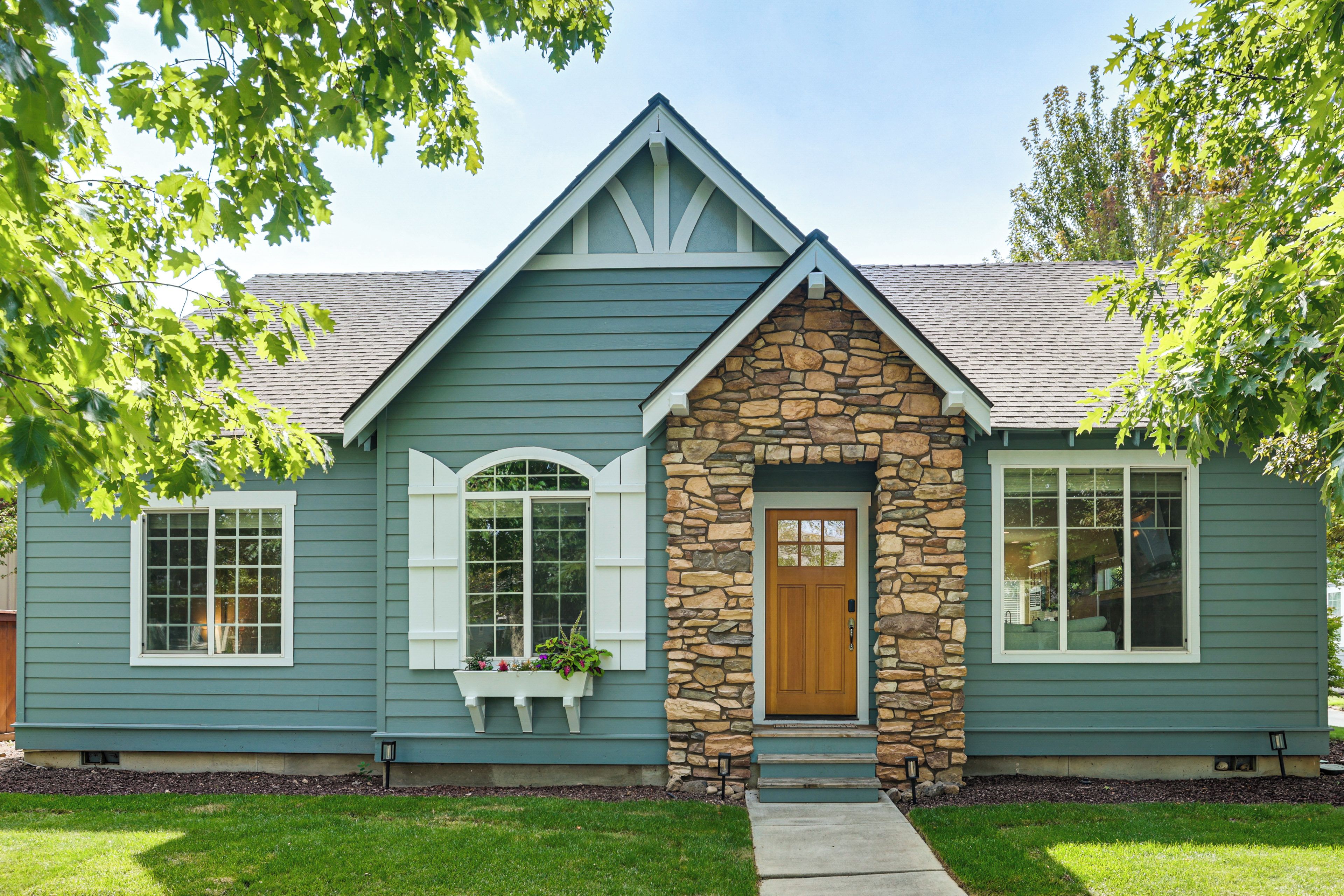 A two-story house with a stone facade and a gabled roof.