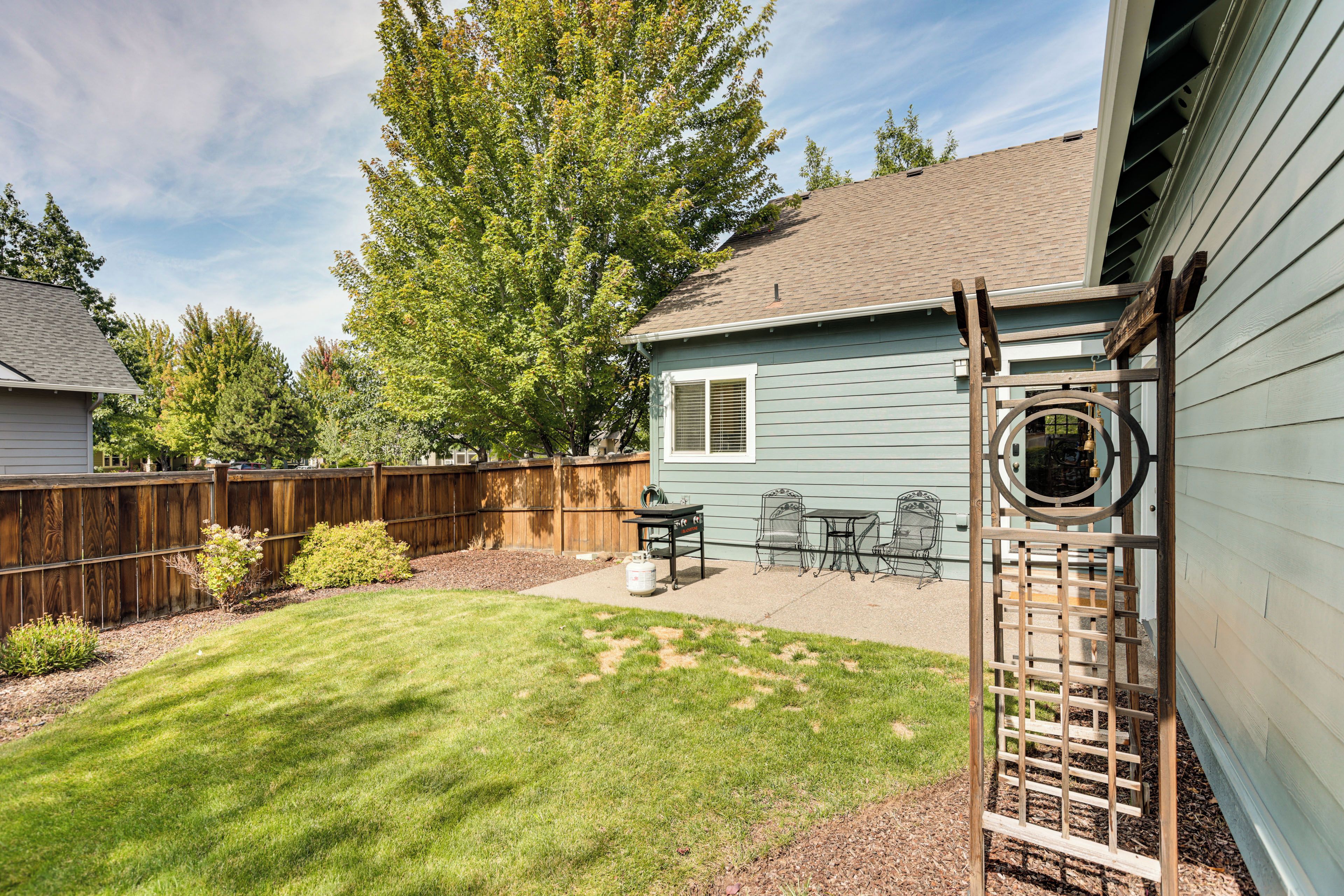 A backyard with a wooden deck, a barbecue area, and a fenced yard.