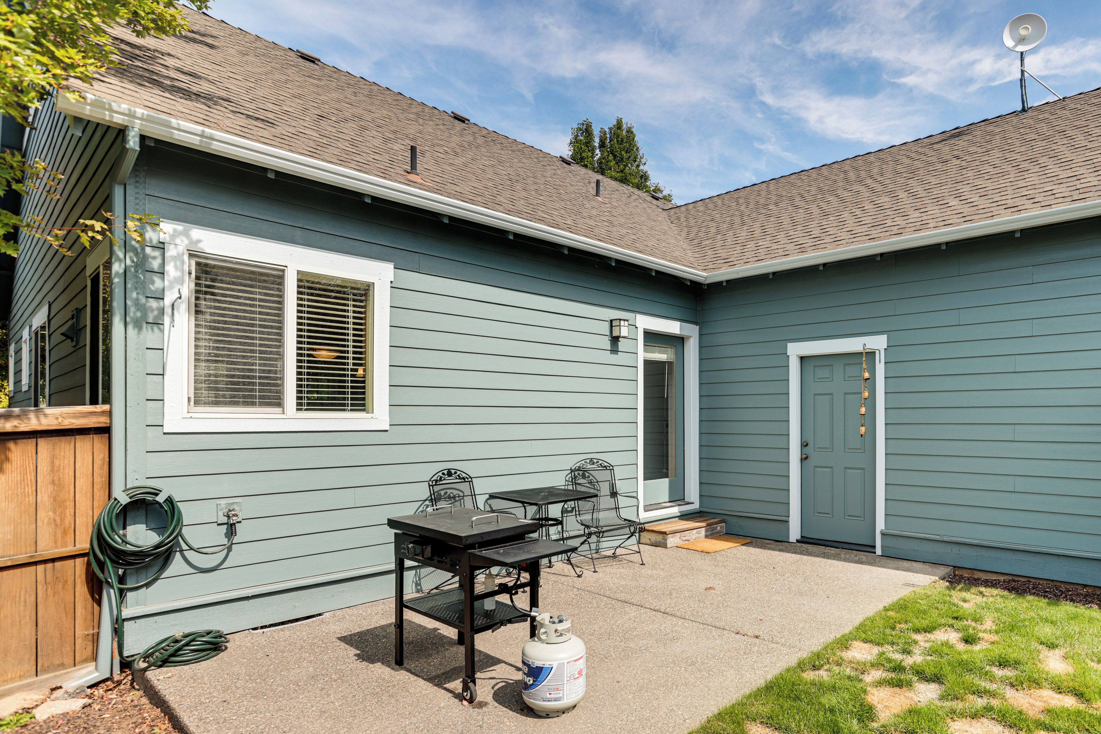 A residential house with a patio area featuring a table and chairs, a door, and a satellite dish on the roof.