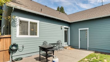 A residential house with a patio area featuring a table and chairs, a door, and a satellite dish on the roof.