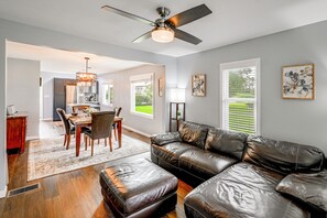 A modern living room with a leather sofa, dining area, and a ceiling fan.