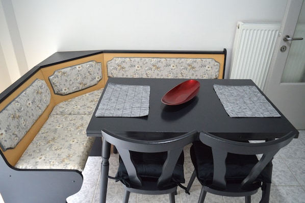 A dining area with a table, chairs, and a bench with floral upholstery.