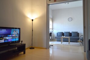 A living room with a television, a floor lamp, a sofa, and a coffee table.