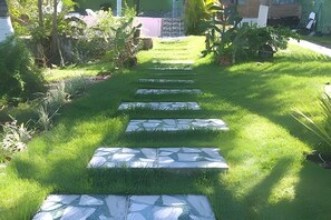 A pathway with stepping stones leading through a grassy area with various plants and trees.