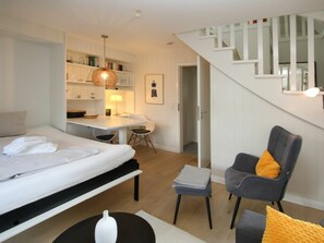 A modern bedroom with a bed, bedside table, and a desk area with a chair. - Luttmarsch 13, Holiday Apartment 10 (Wyk auf Foehr)