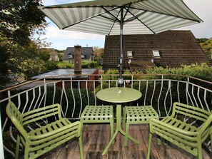 A patio with a table and chairs, a striped umbrella, and a view of houses in the background. - Luttmarsch 13, Holiday Apartment 10 (Wyk auf Foehr)