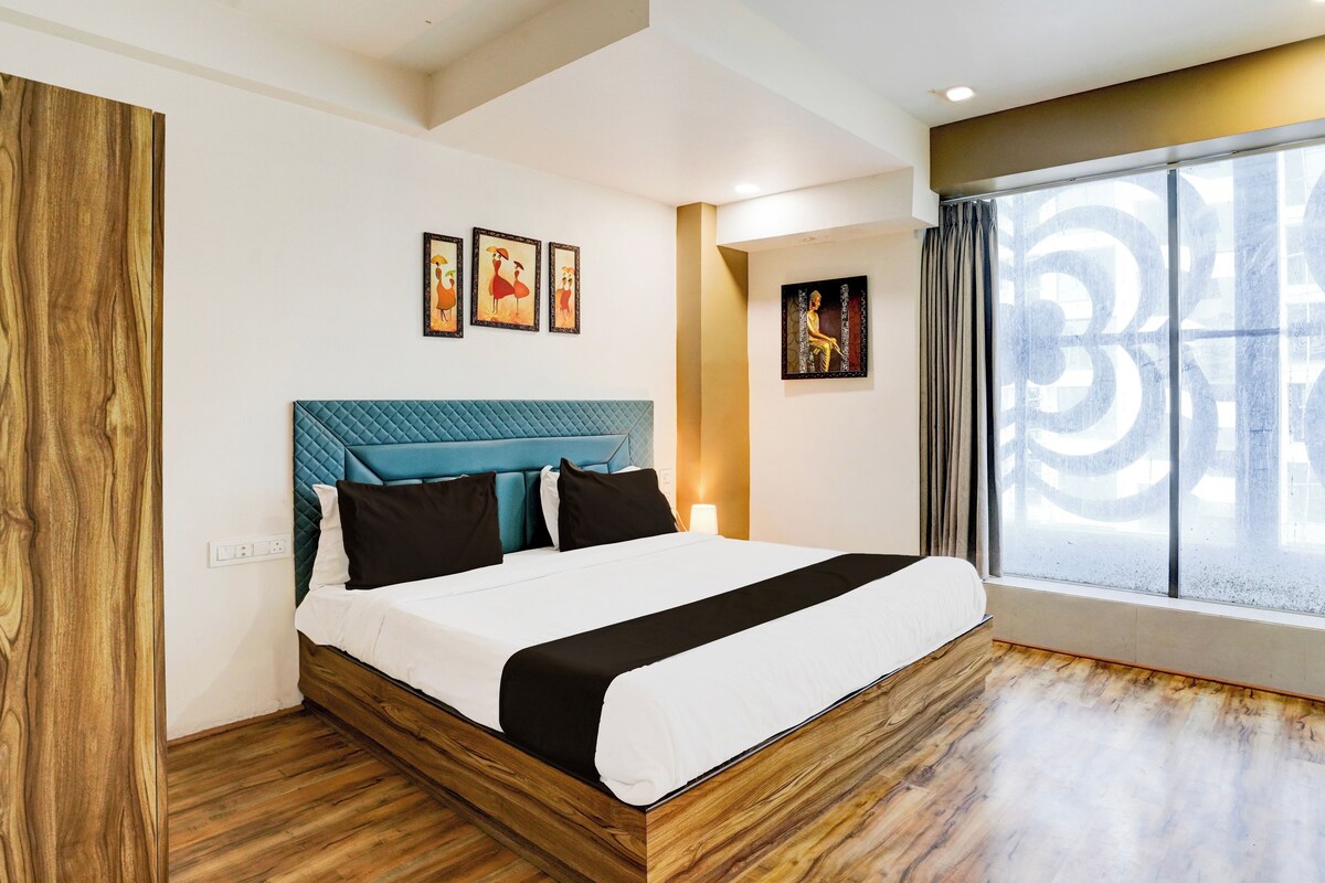 A modern bedroom with a wooden floor, a bed with a blue headboard, and artwork on the walls.