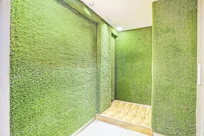 Un baño con paredes de textura verde y suelo de madera.