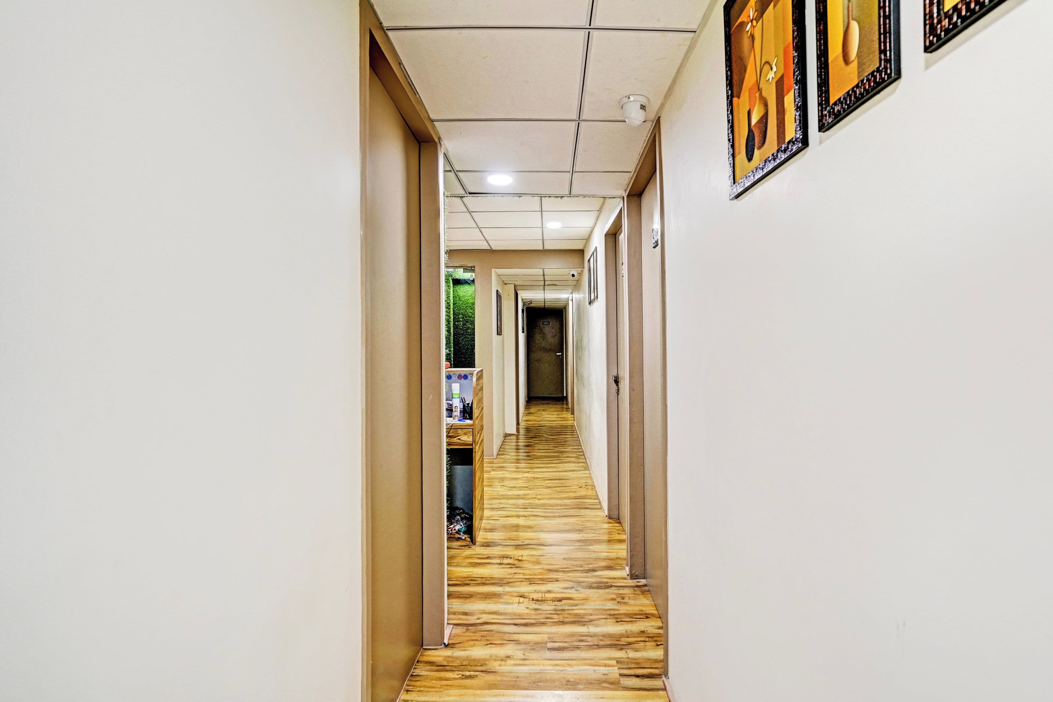 A hallway with a wooden floor, white walls, and a ceiling with recessed lighting.