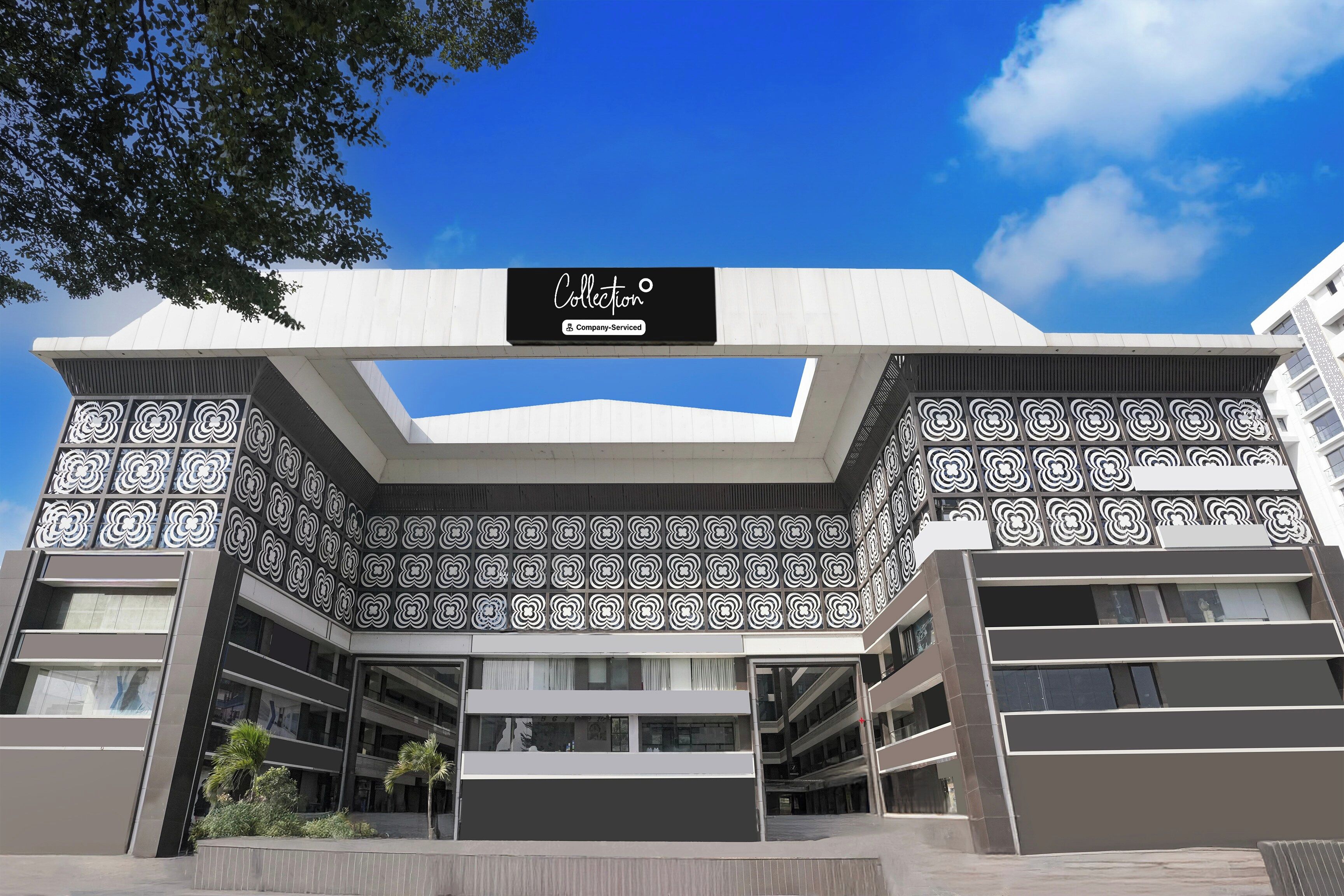 Un edificio moderno con fachada geométrica, un cartel llamativo que dice 'Collection Company-Serviced' y un cielo azul despejado.