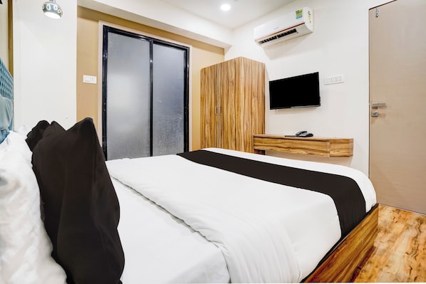 Una habitación de hotel con cama, armario, televisor y aire acondicionado.