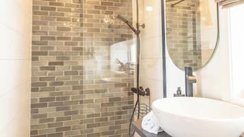 Ein Badezimmer mit Dusche, Waschbecken und Spiegel.