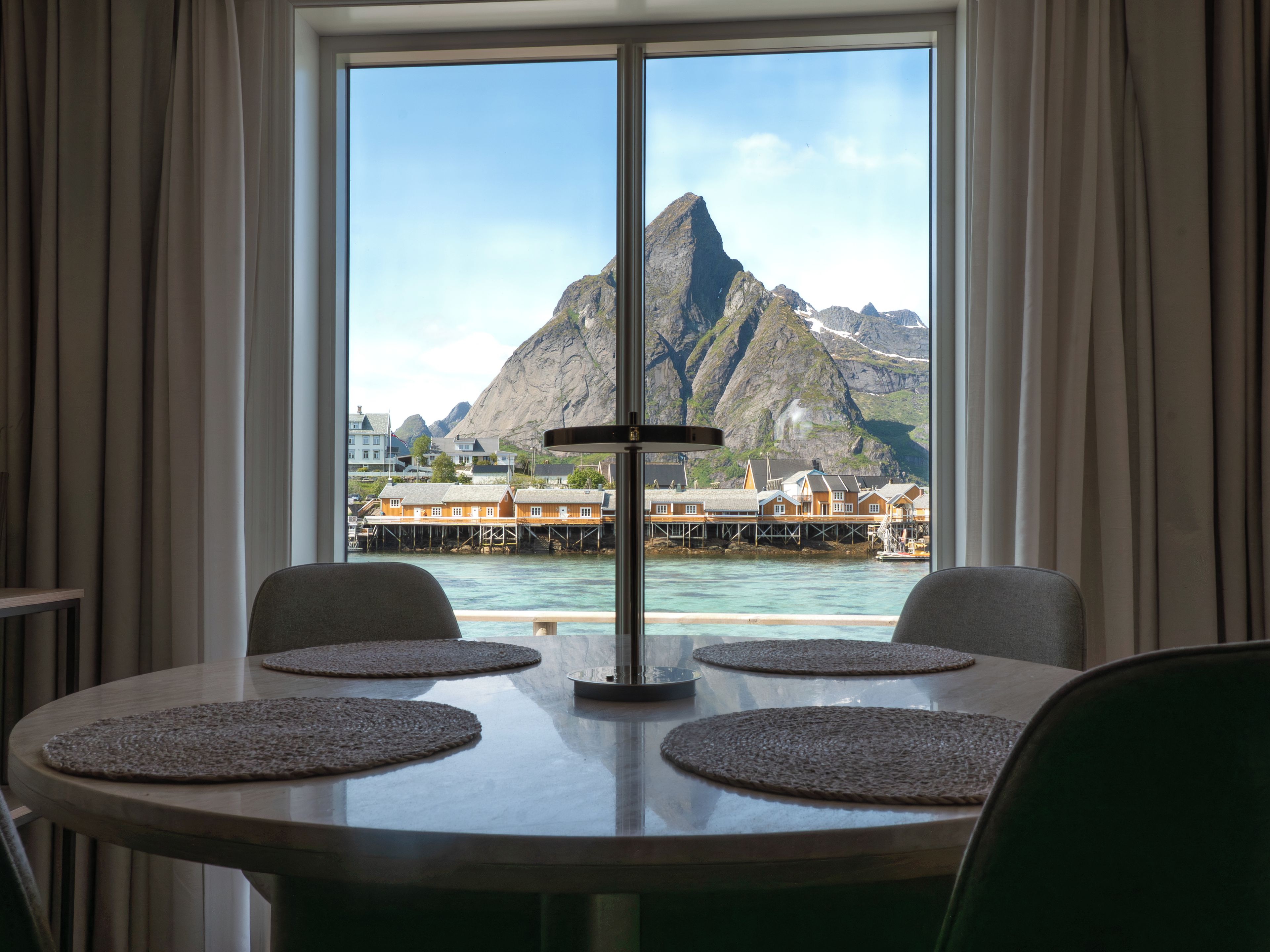 A dining area with a view of a mountain and water.