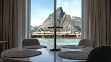 A dining area with a view of a mountain and water.