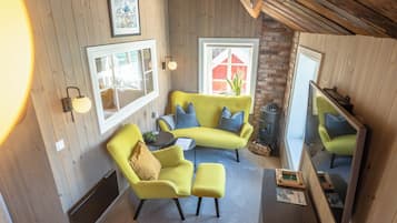 Una habitación acogedora con un sofá amarillo, una mesita y un espejo.