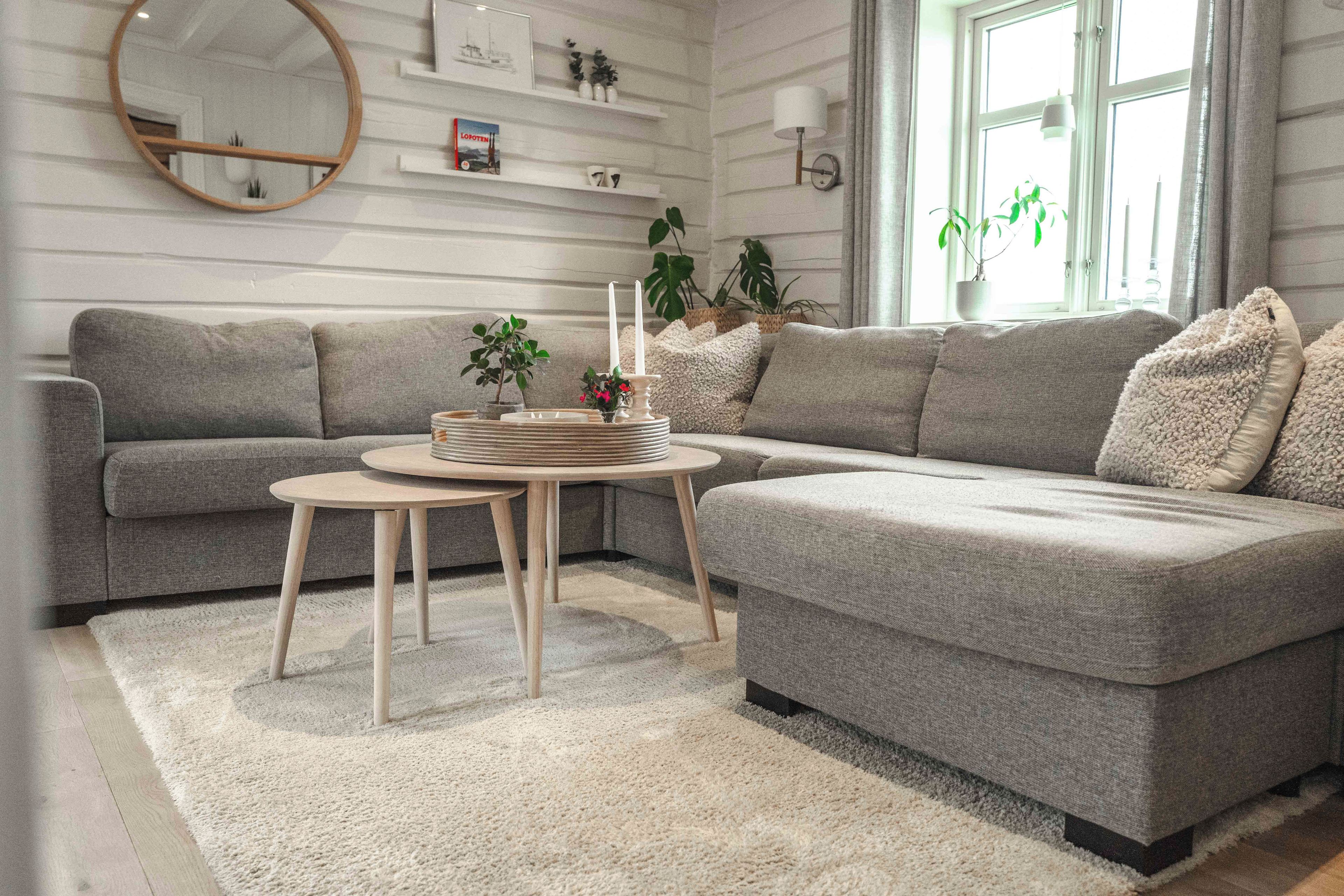 Ein modernes Wohnzimmer mit einer Eckcouch, einem runden Couchtisch und einem kleinen Beistelltisch.