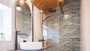 A modern bathroom with a white sink, a large mirror, and a shower with a glass door. - Rostad Retro Rorbuer (Nordland)