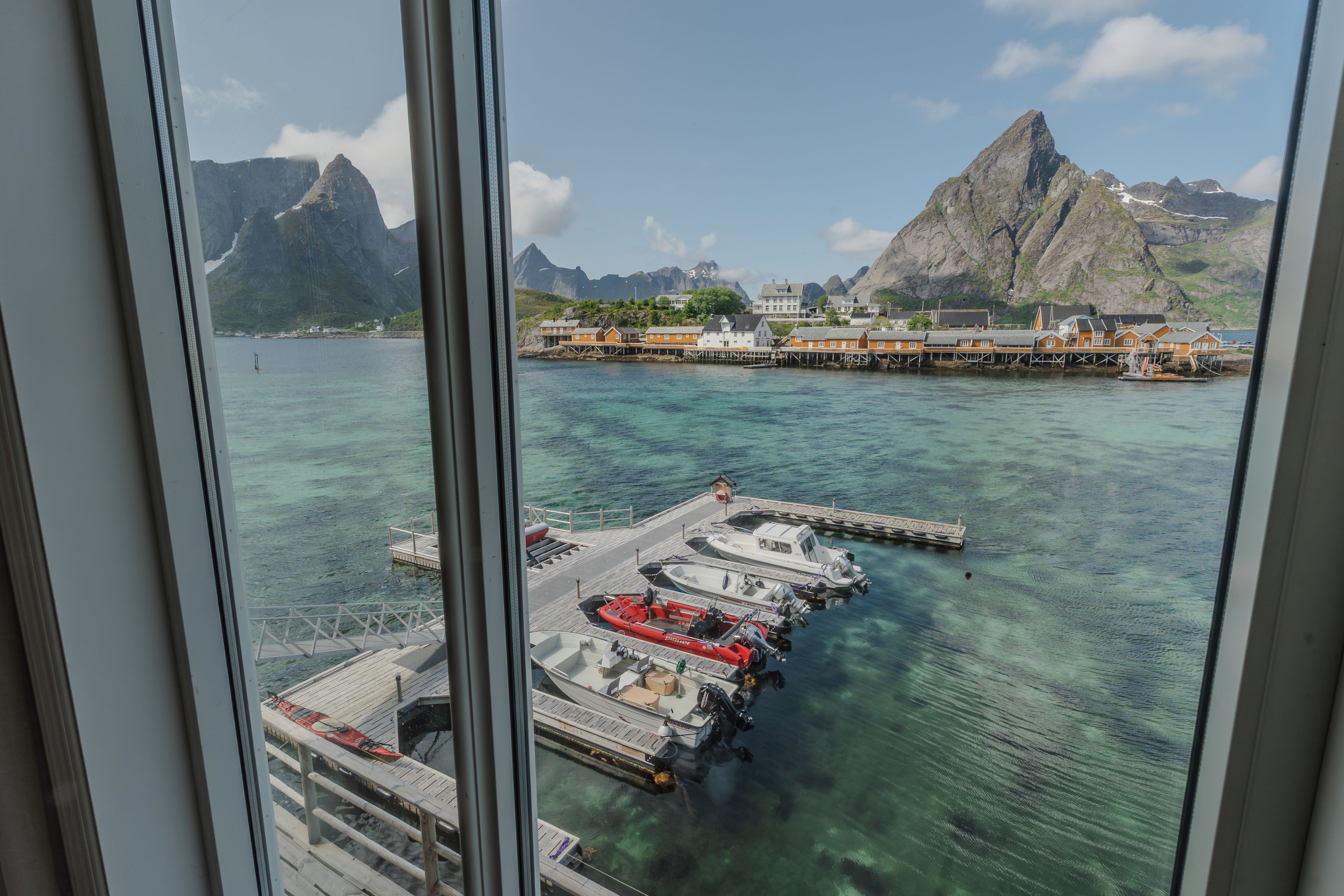 A coastal view with a pier, boats, and a mountainous backdrop.