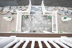 A stone pathway leading to a white wooden structure with a stone wall in the background.