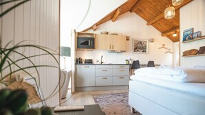 A modern kitchen with wooden cabinets, a microwave, and a sink. - Rostad Retro Rorbuer (Nordland)