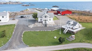 A coastal property with a main house, a red barn, and a parking area with RVs. - Rostad Retro Rorbuer (Nordland)