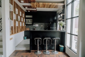 Una cocina moderna con encimera negra, electrodomésticos de acero inoxidable y ventana con vistas al exterior.