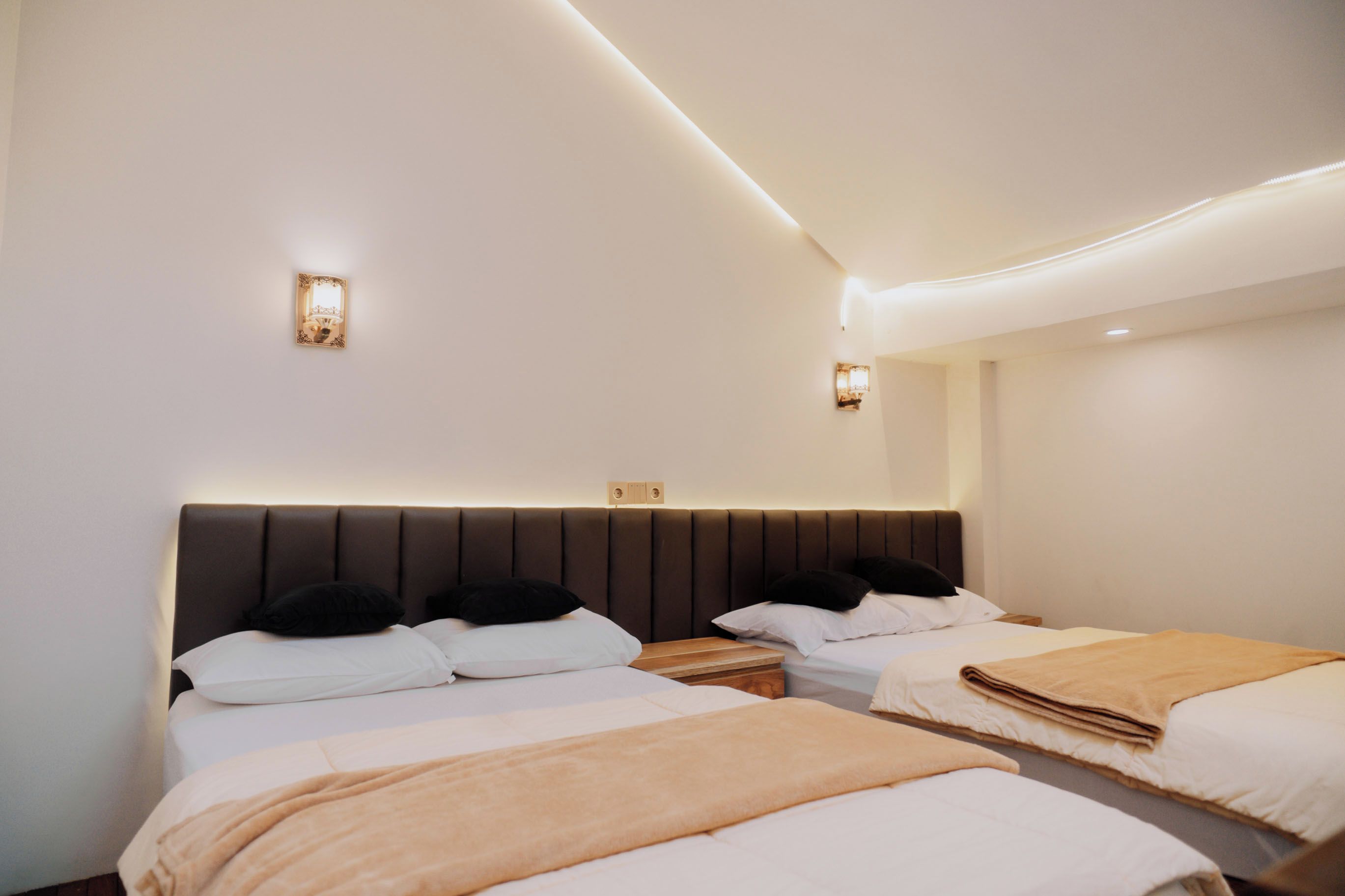 Moderni hotellihuone, jossa on suuri sänky, yöpöydät ja seinään asennetut valaisimet.