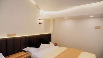 A hotel room with a bed, bedside table, wall-mounted light, and a power outlet.
