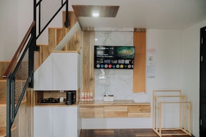 Un interior moderno con una escalera, un televisor de pantalla plana montado en una pared de madera y un letrero de 'NO FUMAR'.