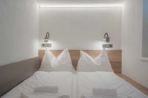 A hotel room with a wooden headboard, two bedside lamps, and a neatly made bed with white linens. - Apartment Haus Dienten - Top 9 (Dienten am Hochkönig)