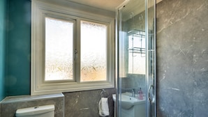 A bathroom with a toilet, sink, and shower area.