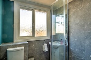 A bathroom with a toilet, sink, and shower area.