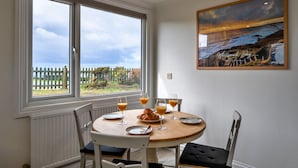 A dining area with a round table, chairs, and a painting on the wall.