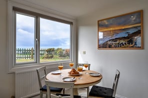 A dining area with a round table, chairs, and a painting on the wall.