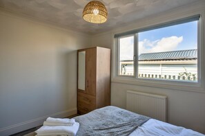 A bedroom with a bed, a wardrobe, a window with a view of the outside, and a ceiling light fixture. - Jesmondene (Freathy)