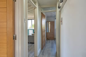 A hallway with wooden doors, a mirror, and a bed in the background.