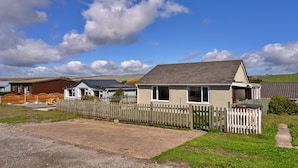 A row of cabins with a wooden fence in front, set in a rural area with a clear sky.