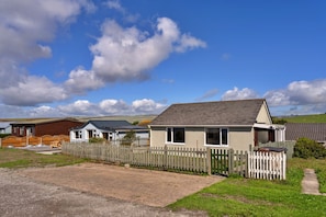 A row of cabins with a wooden fence in front, set in a rural area with a clear sky.
