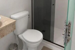 A bathroom with a toilet, a shower enclosure, and a sink. - Pousada Villa Grauçá (Cairu)