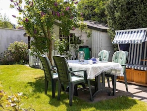 An outdoor dining area with a table, chairs, and a striped awning. - 3 in the House Sturmmowe (St. Peter-Ording)