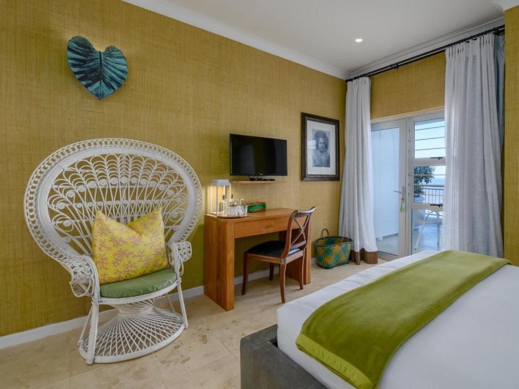 A hotel room with a bed, a desk with a chair, a television, and a window with curtains.