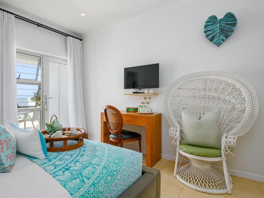 A hotel room with a bed, a television, a desk, a chair, and decorative wall art.