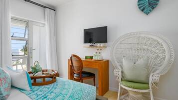 A hotel room with a bed, a television, a desk, a chair, and decorative wall art.