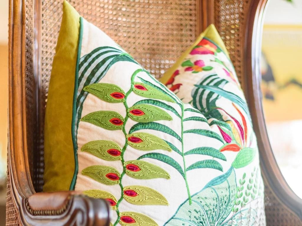 Una silla con respaldo tejido y dos almohadones decorativos con diseños bordados.