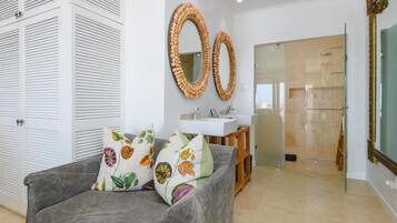 A modern bathroom with a glass shower, a white sink, and a mirror with a woven frame.